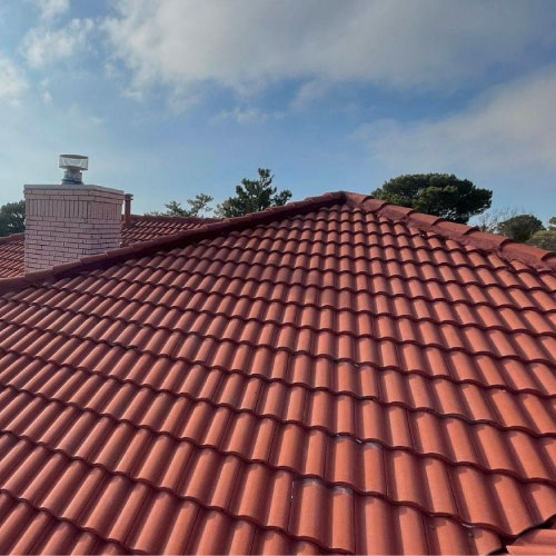 Close-up of finished red clay tile roof under blue sky